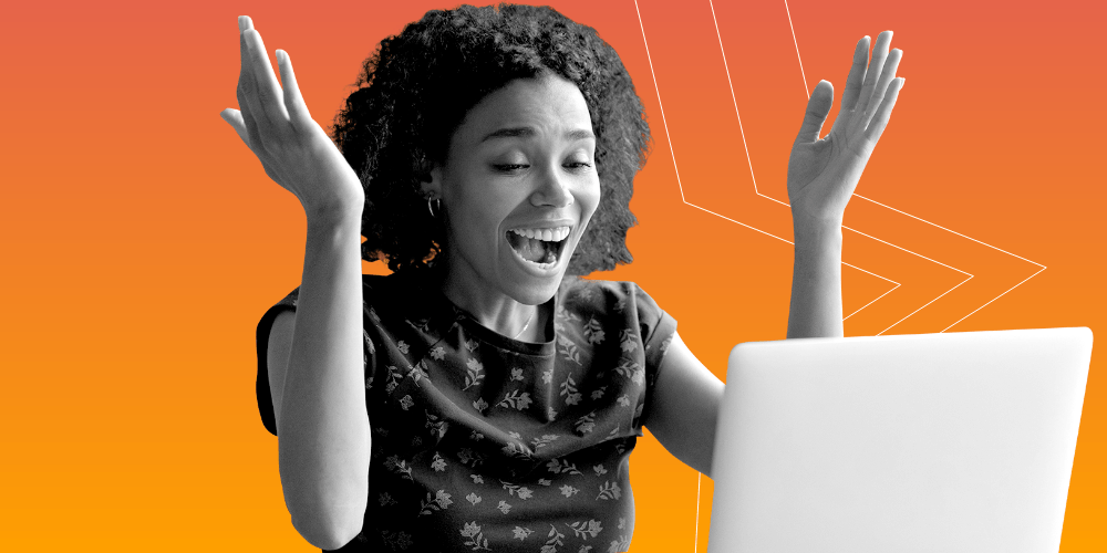 Woman smiling with her hands in the air in front of a computer.