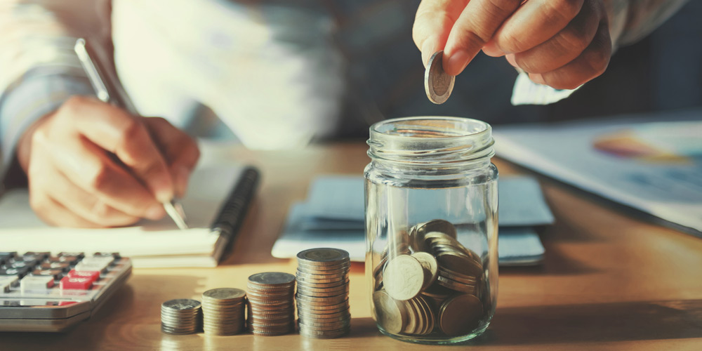 Hands putting coins in a jar
