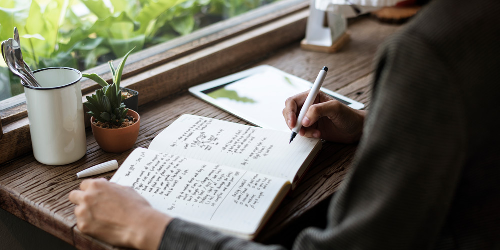 Hands writing in a journal