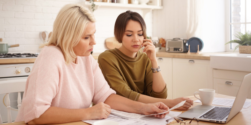 Mother and daughter looking at bills at the kitchen counter