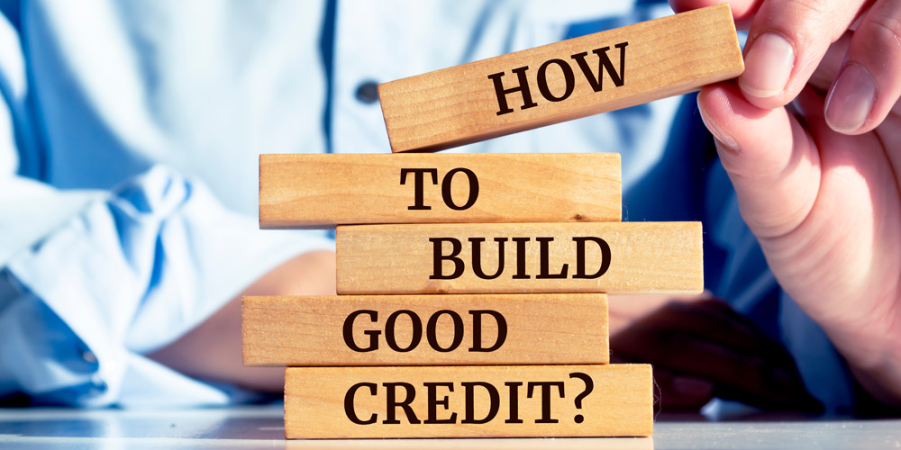 Hands stacking blocks that say "How to build good credit?"