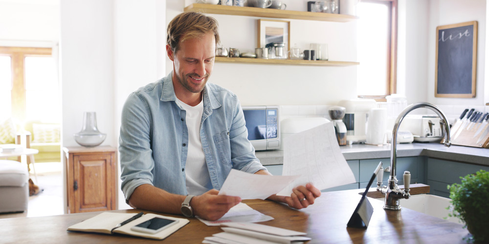 Man looking at papers at the kitchen counter