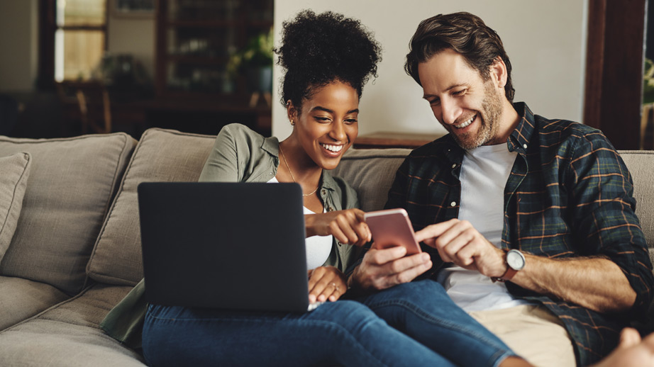 Couple laughing while looking at a phone on the couch