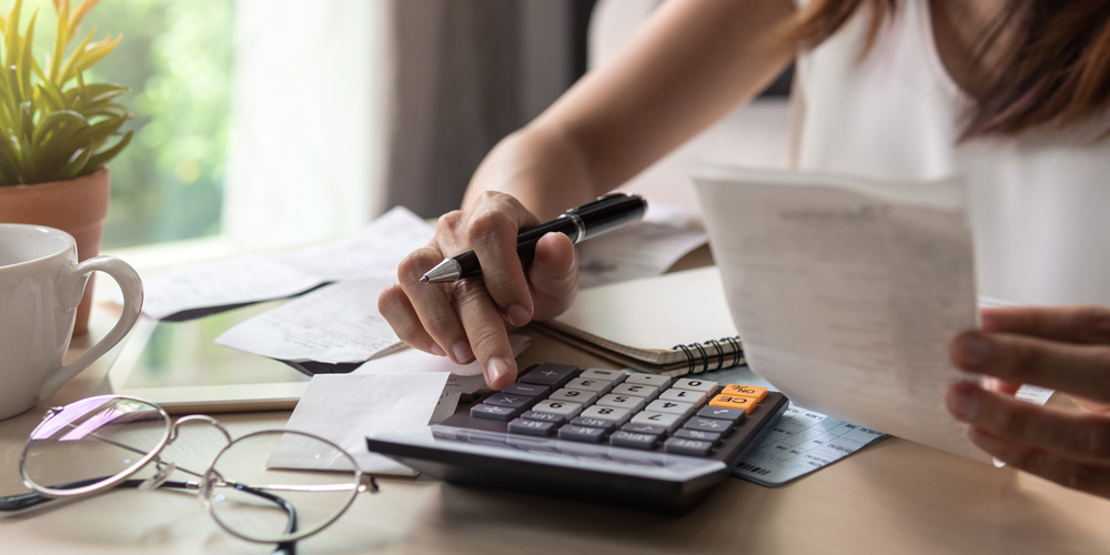 Hand holding a pen and typing on a calculator