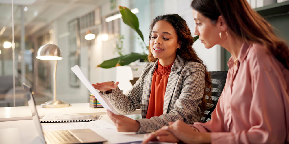 Woman in a plaid sportcoat explaing a concept to her client