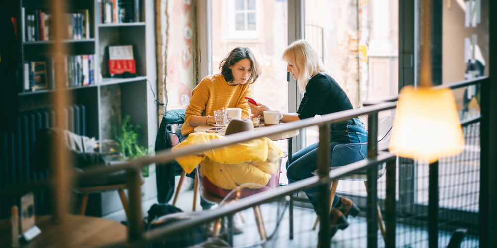 Two women talking at a small table at a coffee shop