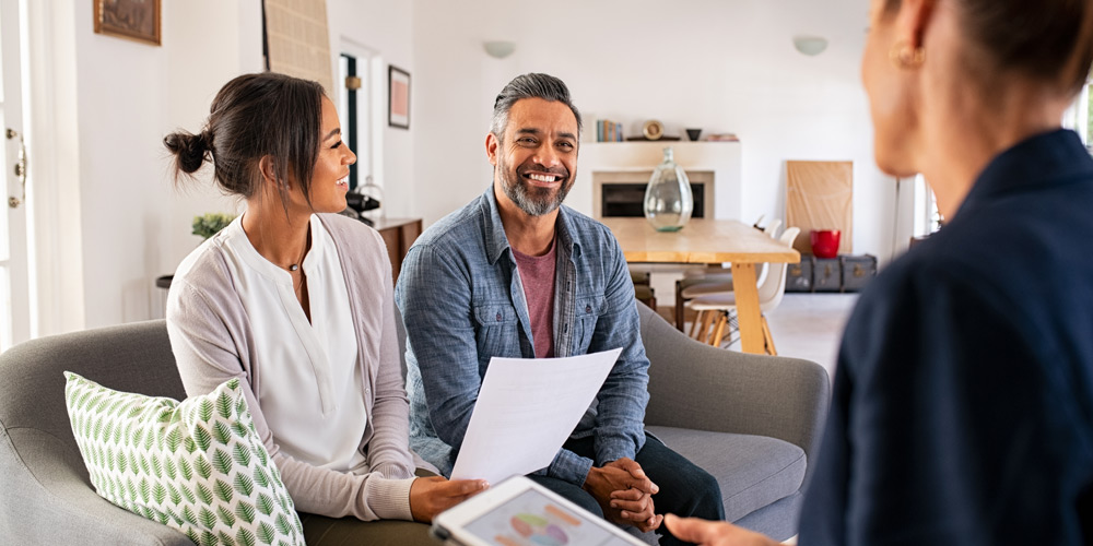 Young couple sitting on a couch while talking to a financial advisor