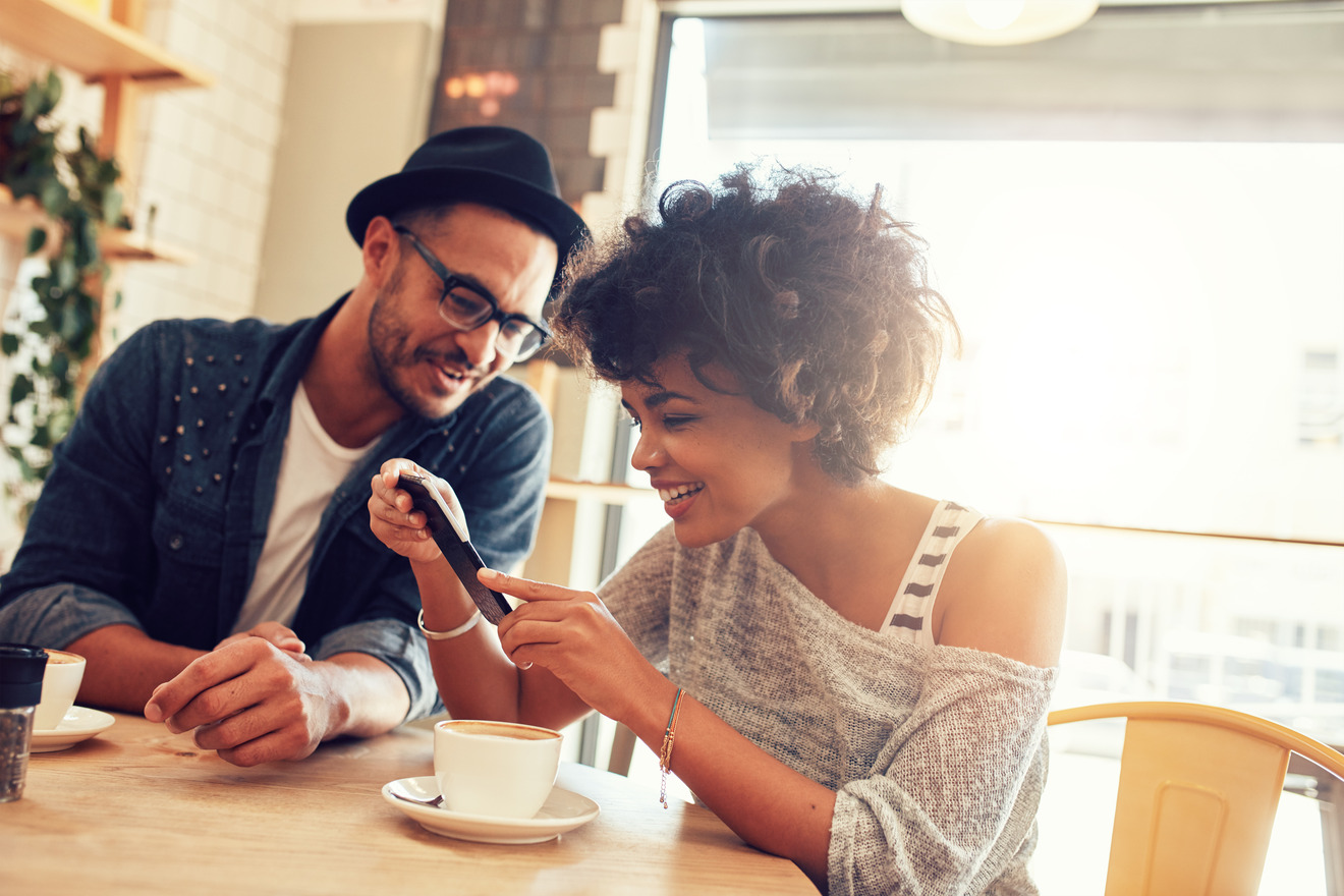 man and woman looking at mobile phone at coffee shop