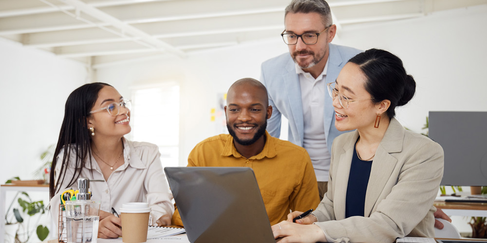 Coworkers huddled around a laptop