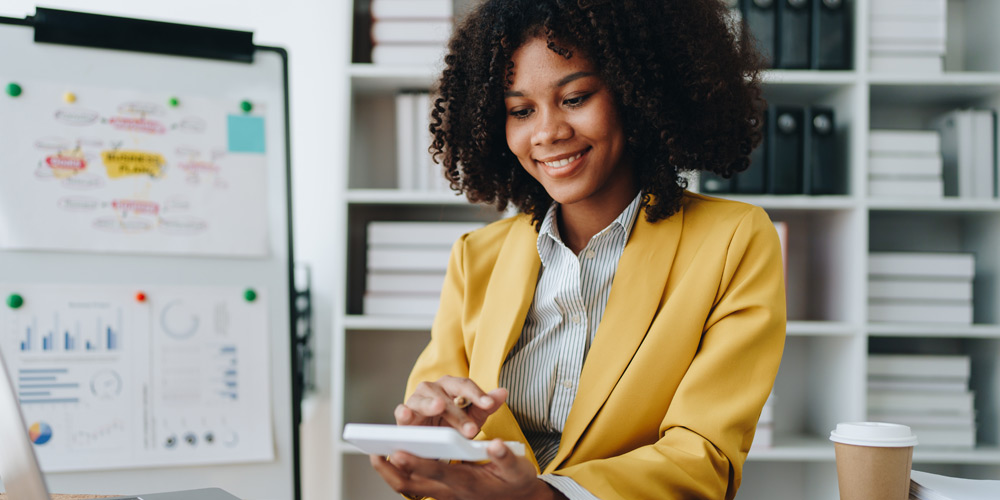 Woman in a yellow sport coat using a calculator