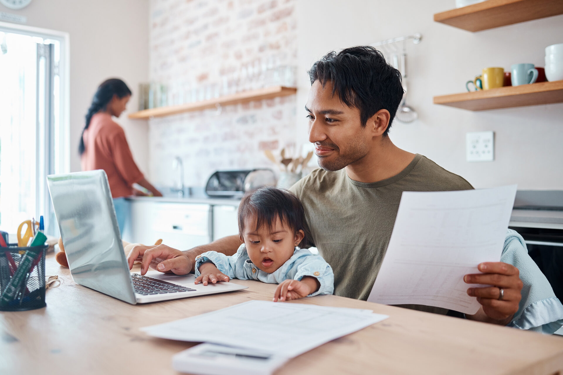 Man working on computer with baby in his lap