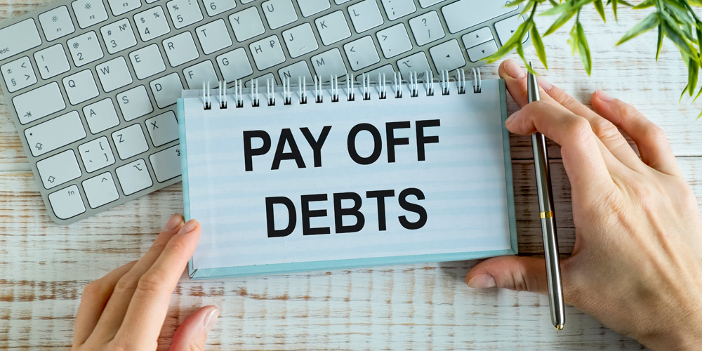 Hands holding a card that reads "pay off debts"