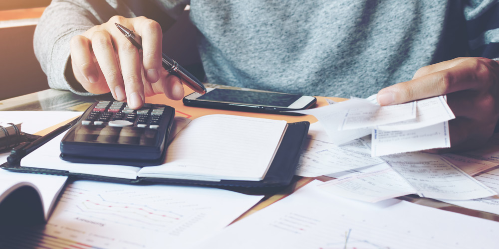 Hands holding receipts and typing on a calculator