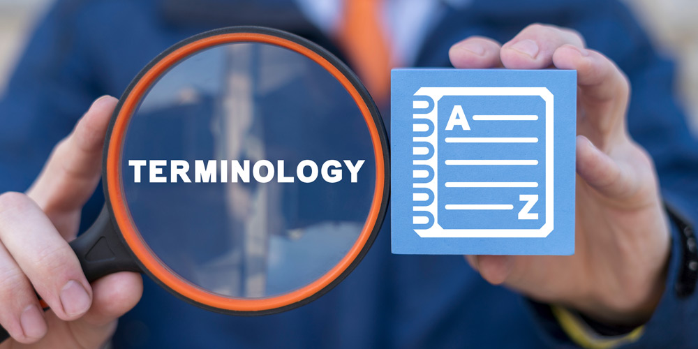 Hands holding a notepad and magnifying glass that says "Terminology"